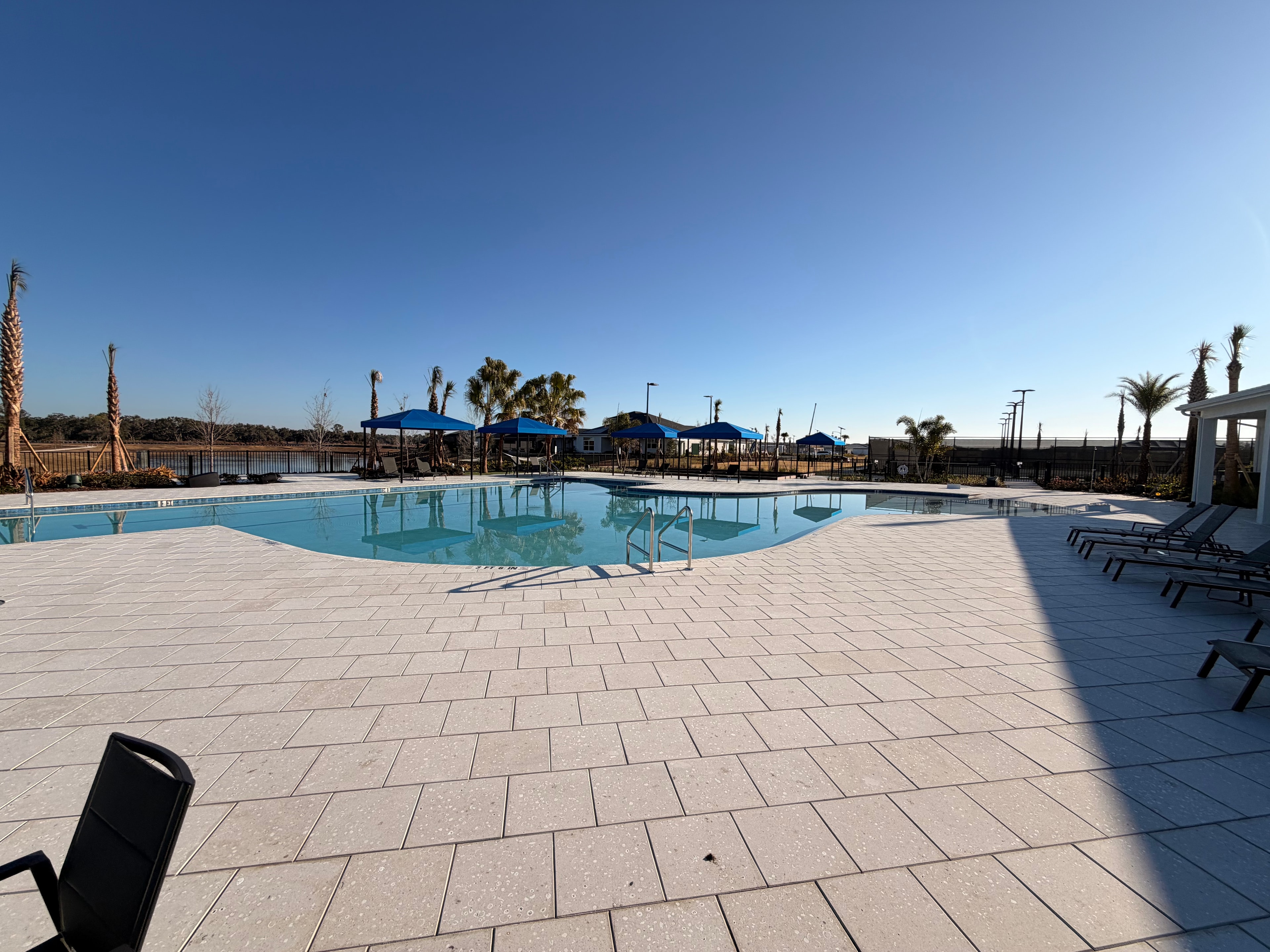 Community pool with blue umbrellas and palm trees